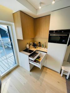 eine Küche mit weißem Kühlschrank und Holzschränken in der Unterkunft Marè studio in Neringa