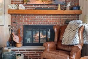 a living room with a brick fireplace with a leather chair at Gasthaus Fox by Juniper Holiday + Home in Bridgman