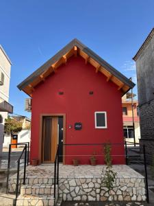 a red building with a red door in front at Rosea LOFT in Përmet