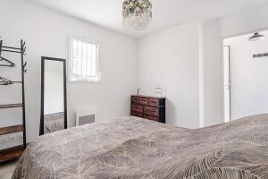 a white bedroom with a large bed and a mirror at Les deux pauses in Martigues