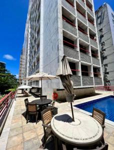 a patio with a table and chairs and an umbrella at HOTEL NAVEGANTES VISTA PARA MAR Boa Viagem in Recife