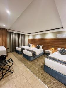 a hotel room with three beds and a desk at شقق سكنية بابو ذر الغفاري in Medina