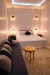 a bedroom with a white bed and a couch at Chez BABAYO BY DADES in Zaouïet Sidi Daoud