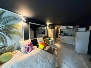 a bedroom with a bed with colorful pillows and a kitchen at Le Must - Chambre double entre Paris et Disney in Livry-Gargan