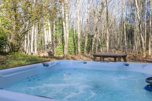 a hot tub with a picnic table in the woods at The Coyote by Juniper Holiday + Home in Saugatuck