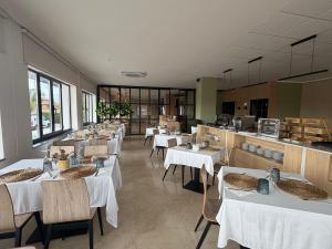 a restaurant with white tables and chairs and a kitchen at Hotel Valjunco in Valencia de Don Juan