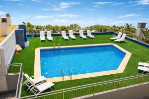 a swimming pool on the roof of a building with lounge chairs at La Loma in Águilas