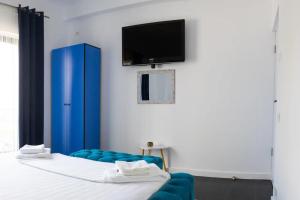 a room with a bed with a blue chair and a tv at Solemar Boutique in Eforie Sud