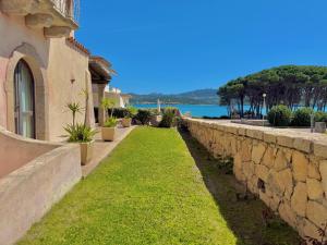 a stone wall next to a building with a yard at Villa Rosa in Cannigione