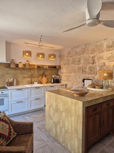 a kitchen with white cabinets and a stone wall at Mi Casa 4 in Jávea