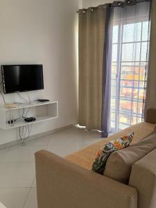 a living room with a couch and a flat screen tv at Urban Praia Maria - ApartHotel in Praia