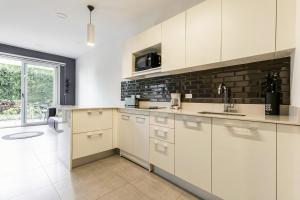 a kitchen with white cabinets and a brick wall at Urban Flats Studios by Corporate Stays in San José