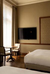a hotel room with a bed and a table and a tv at Grand Jardin Hotel in Baku