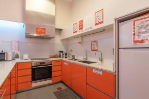 a kitchen with orange cabinets and a sink and a refrigerator at Porto Lounge Hostel & Guesthouse by Host Wise in Porto