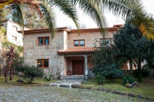 a stone house with a palm tree in front of it at Casa Das Flores in Amares