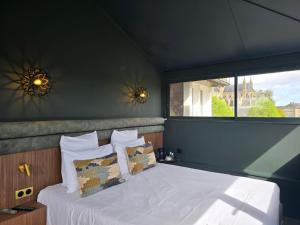 a bedroom with a white bed with a window at Le Castel Guesthouse in Bayeux