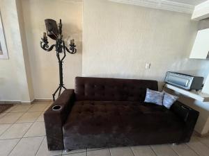 a living room with a brown couch and a tv at Birdhouse in Guanajuato