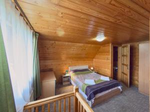 a bedroom with a bed in a wooden cabin at Casa de vacanta ROUA DIMINETII in Beclean