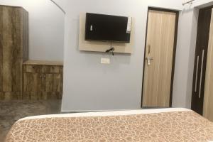 a bedroom with a bed and a flat screen tv on a wall at The Aura - Backpacker Stop in Nainital