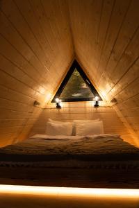 a bed in a wooden room with a window at ULISI house in Verkhniy Yasenov