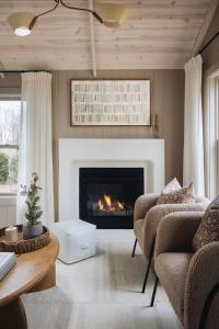 a living room with a fireplace with two chairs and a table at Townie 1 - The Ivy by Juniper Holiday + Home in Union Pier
