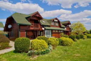 a wooden house with a green roof and some bushes at Casa de vacanta ROUA DIMINETII in Beclean