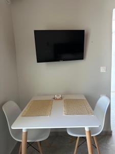 a white table with chairs and a tv on a wall at Mamour Apartments in Mavrovouni in Mavrovouni +21 photos