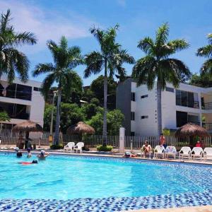 a swimming pool with palm trees and people in it at Apartasol Santafe de Antioquia in Santa Fe de Antioquia