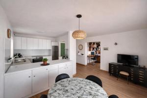 a kitchen with white cabinets and a table in a room at Terraza con vistas al mar Tenerife Norte Mesa del Mar in Tacoronte