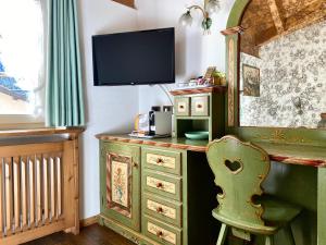 a room with a desk with a television and a chair at Garnì Stella Alpina in Canazei