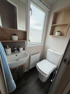a bathroom with a toilet and a sink and a window at Rosies by the Sea in Walton-on-the-Naze +5 photos