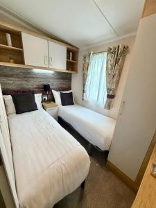 a small room with two beds and a window at Rosies by the Sea in Walton-on-the-Naze