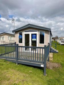 a small building with a fence in the grass at Rosies by the Sea in Walton-on-the-Naze