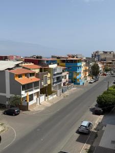 a city street with buildings and cars on a road at Urban Praia Maria - ApartHotel in Praia