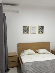 a bedroom with a bed and three pictures on the wall at Urban Praia Maria - ApartHotel in Praia