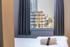a bed with a pillow in front of a window at easyHotel Cardiff in Cardiff