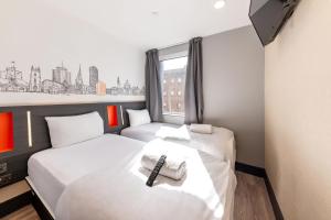 two beds in a small room with a window at easyHotel Cardiff in Cardiff