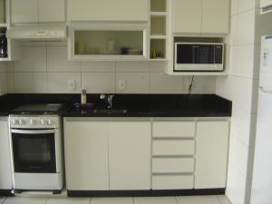 a kitchen with white cabinets and a sink and a microwave at Apartamento em Praia dos Ingleses in Florianópolis