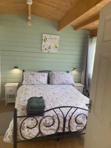 a bed in a bedroom with a green wall at Modern Cabin with large private garden in Old Romney