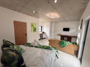 a bedroom with a large bed with a couch at Our Little Cottage in George