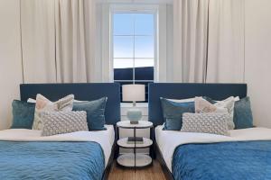 two beds with blue and white pillows in a room at Luxe 19BR Combo & Private Backyard with Pool in New Orleans