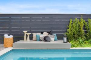a bench next to a swimming pool with pillows at 7BR City Condo & Pool Access Near CBD in New Orleans
