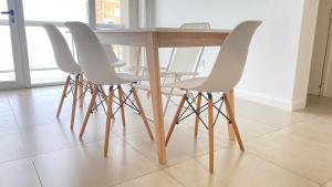 a wooden table with four white chairs around it at Bella Vista in Puerto Madryn +28 photos