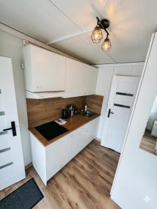 a kitchen with white cabinets and a sink at Domki303 in Mszczonów