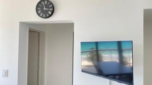 a clock on a wall next to a flat screen tv at Bella Vista in Puerto Madryn