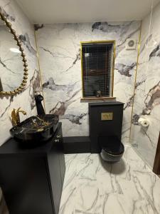 a bathroom with a black sink and a marble wall at Barnfields Retreat in Little Clacton +31 photos