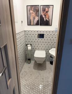 a bathroom with a toilet and two pictures on the wall at Rodzinna Przystań Arkadia in Dominice +33 photos