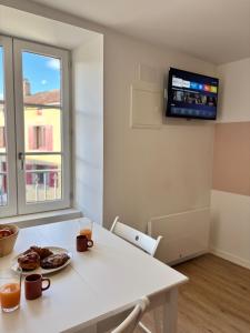 a white table with a plate of food and a tv on a wall at Studio Le Dolmen Château-Larcher Arrivée autonome in Château-Larcher