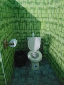 a bathroom with a toilet in a green tiled wall at Hostal viroleño in Zacatecoluca +17 photos
