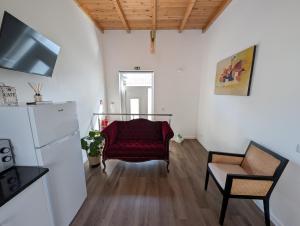 a living room with a red chair and a refrigerator at Casas Albano 1 in Caldas da Rainha
